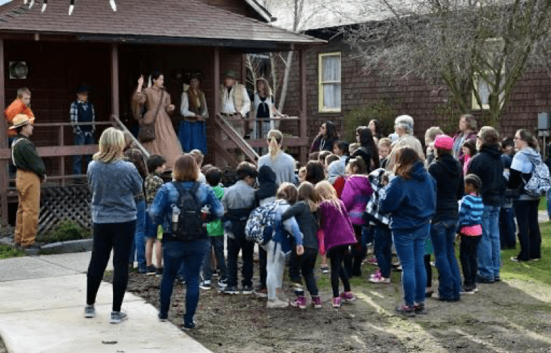 Group gathers around a docent in 1900s dress to hear about the history of the Gold Mining era.